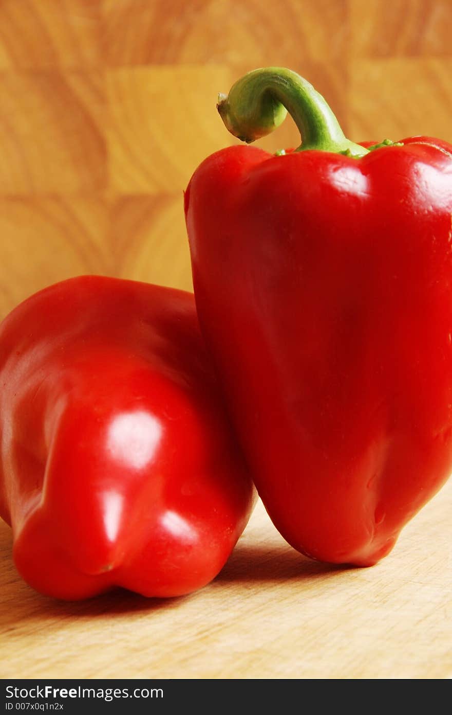 Two red peppers on a wooden board. Two red peppers on a wooden board.