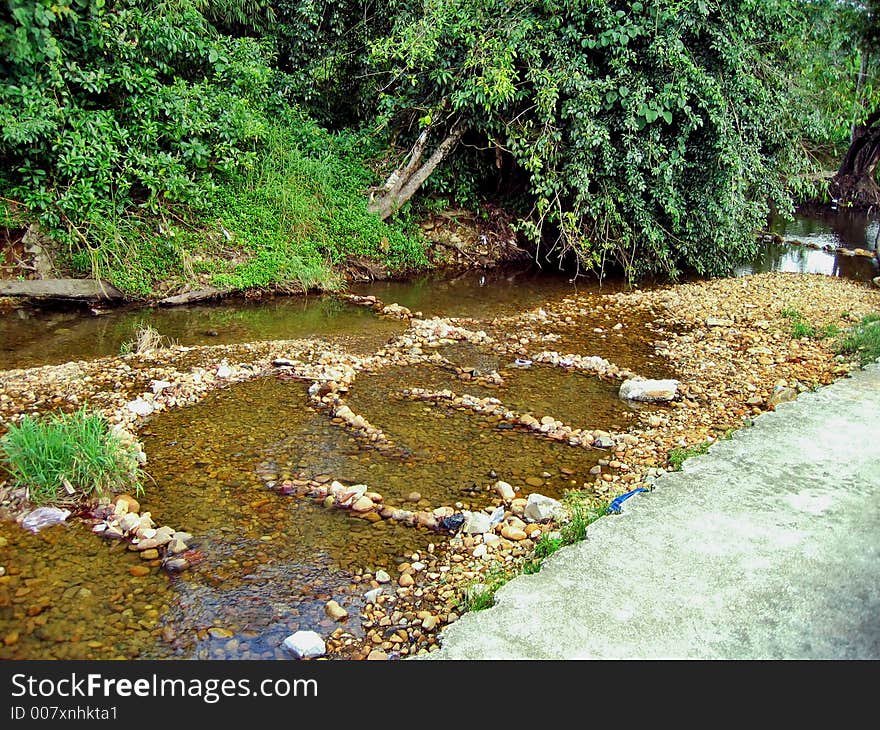 A tropical scene of a freshwater river flowing over big rounded pebbles. It's sad to see some irresponsible people leaving behind they rubbish into this river. A tropical scene of a freshwater river flowing over big rounded pebbles. It's sad to see some irresponsible people leaving behind they rubbish into this river.