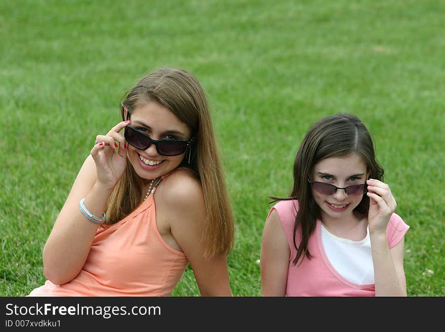 Two girls pulling down sunglasses. Two girls pulling down sunglasses