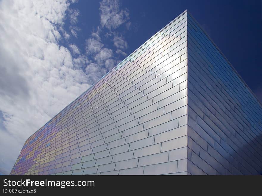 The face of a modern titanium-clad building against a blue sky. The face of a modern titanium-clad building against a blue sky