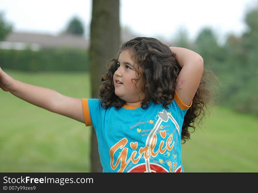 The little girl standing beside a tree. The little girl standing beside a tree