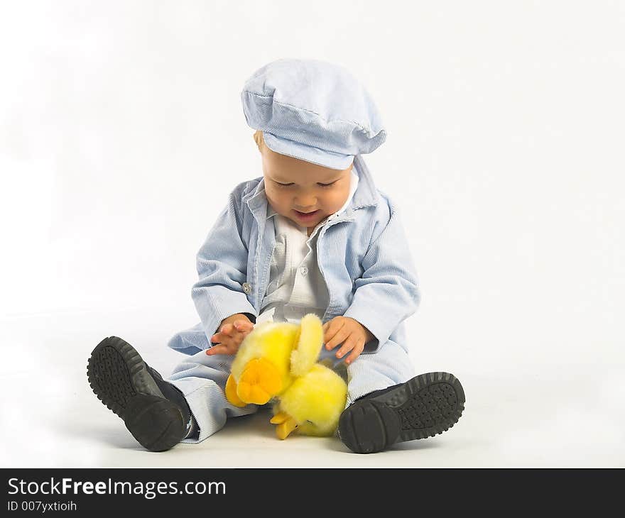 Little boy with yellow toy. Photo in studio. White background