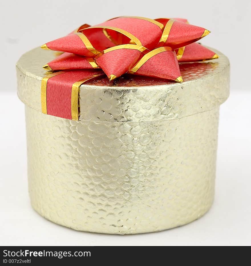 Little golden present box with big red bow on top. Little golden present box with big red bow on top.