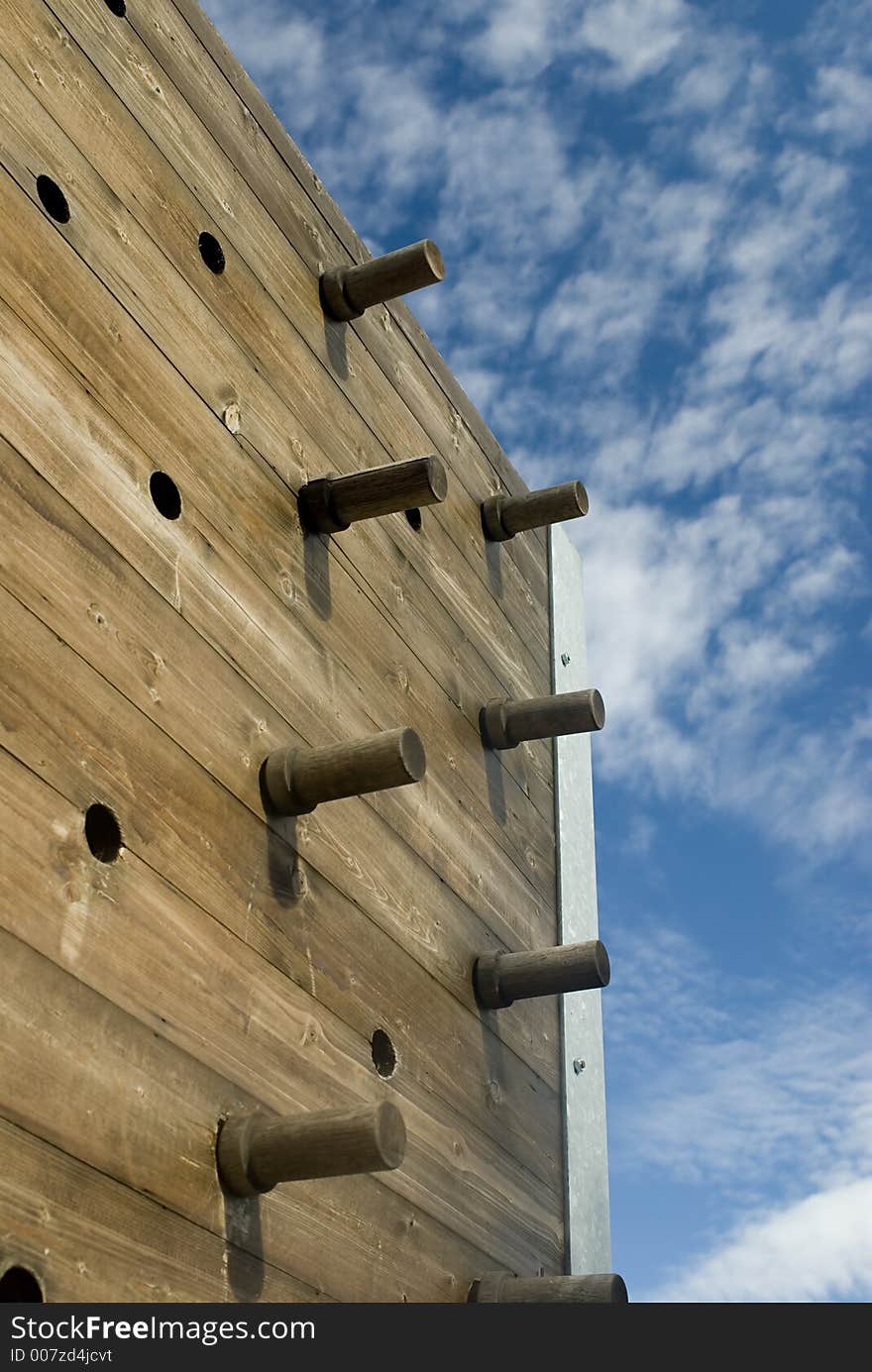 A wooden climbing wall with pegs.