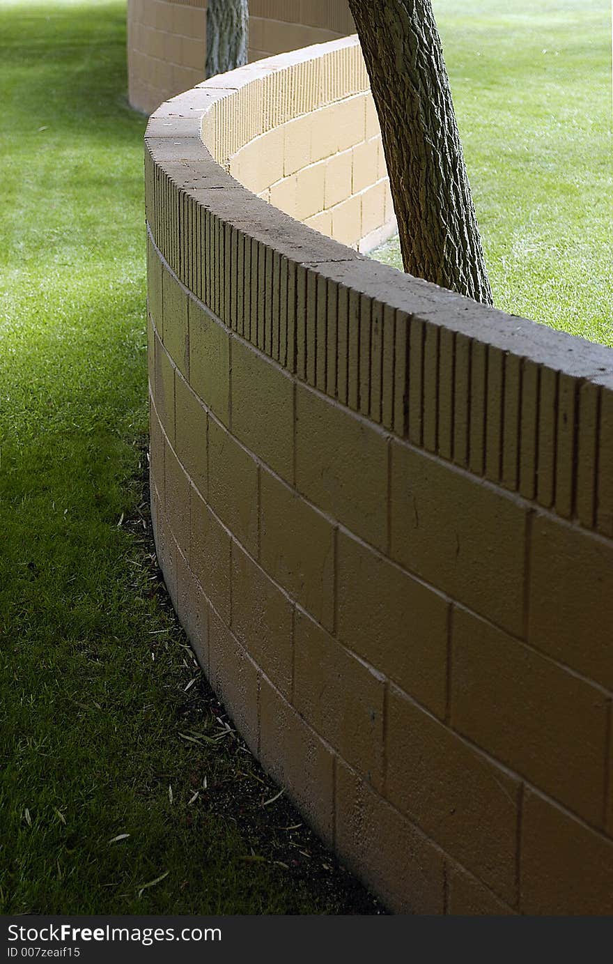 An unusual S-shaped brick wall among tree trunks and well cared for lawn. An unusual S-shaped brick wall among tree trunks and well cared for lawn