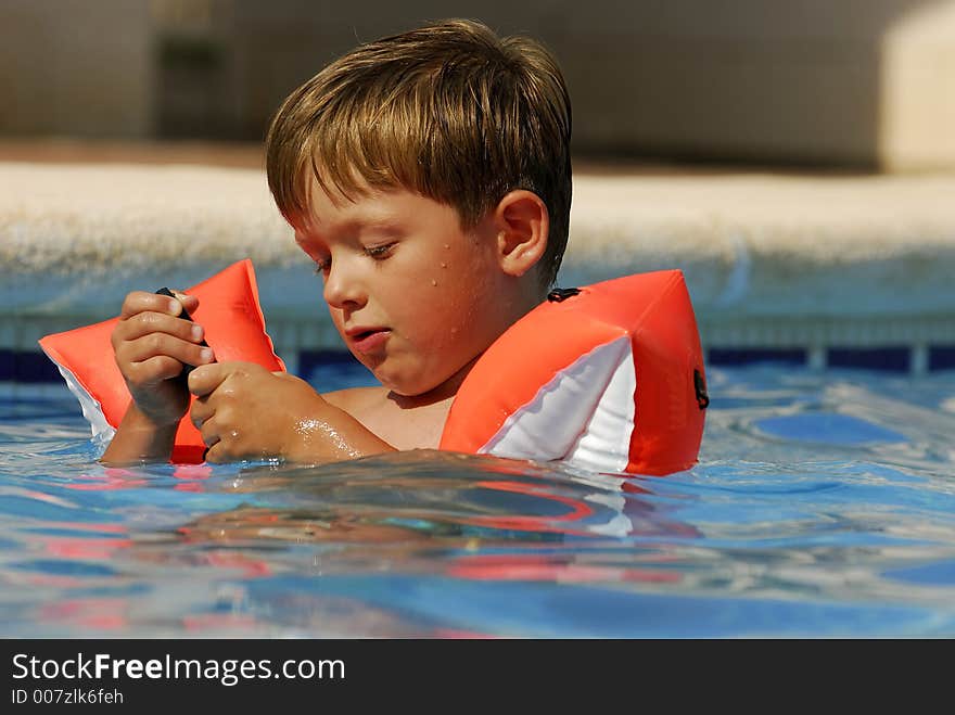 Boy child makes a call with a cell-phone in a swimming-pool. Boy child makes a call with a cell-phone in a swimming-pool