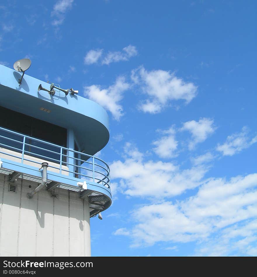 Blue painted bridge tower with deeper blue sky and white clouds.