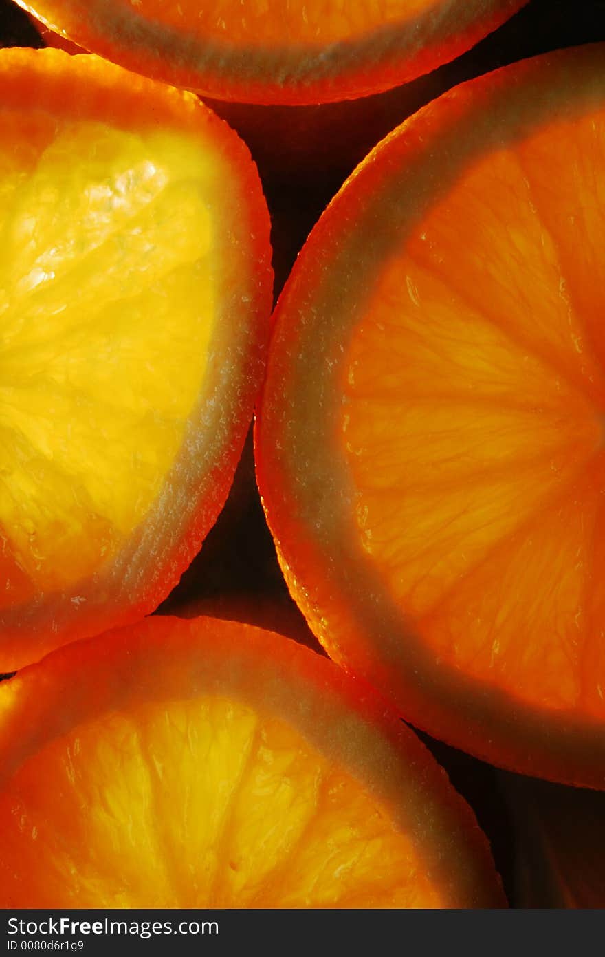 Slices of orange on black background, lit from underneath. Slices of orange on black background, lit from underneath