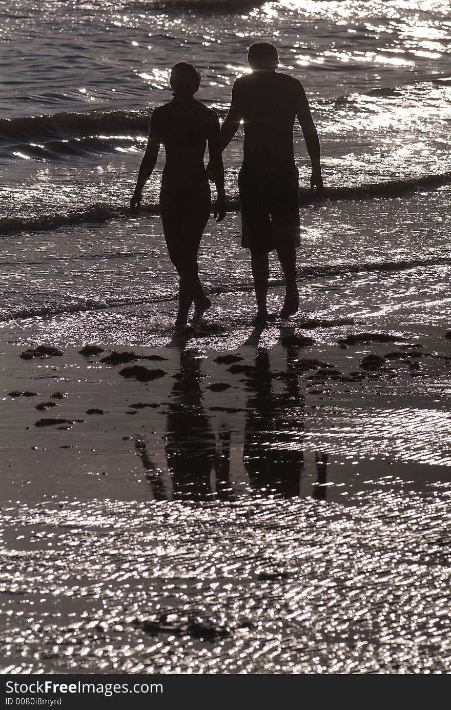 Young couple walking in the surf at the beach. Young couple walking in the surf at the beach.