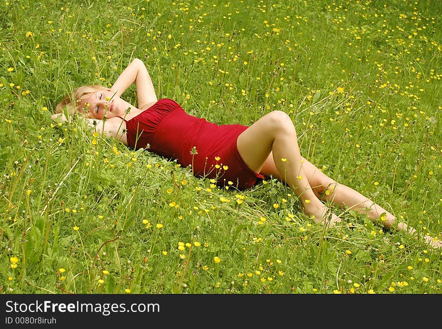 Red haired girl lying between yellow flowers and grass. Red haired girl lying between yellow flowers and grass.