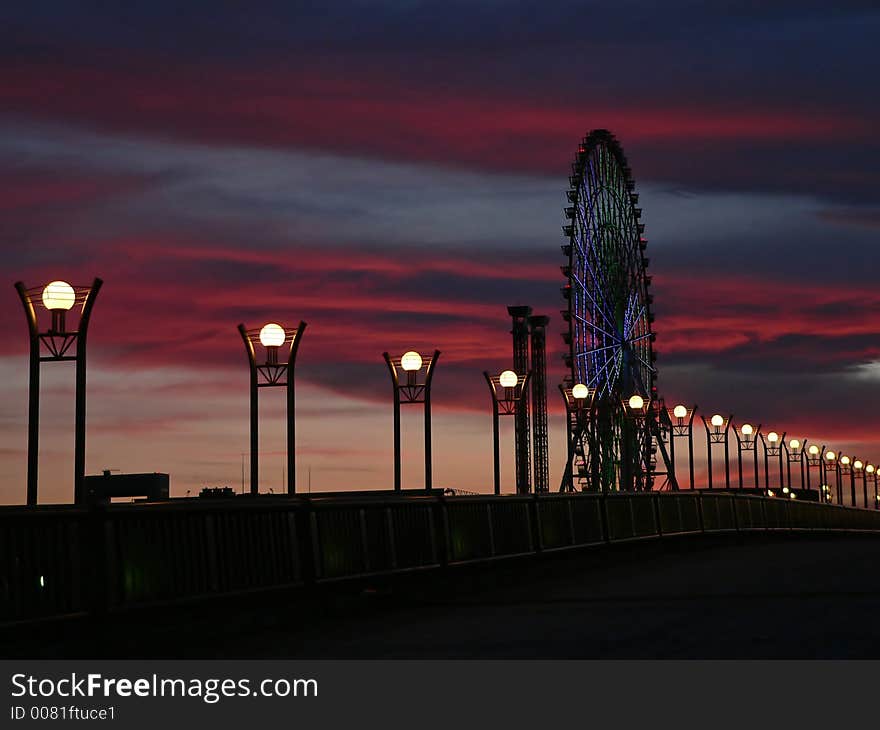 Twilight cityscape with row of light posts and big-wheel on the dramatic sky background, Tokyo. Twilight cityscape with row of light posts and big-wheel on the dramatic sky background, Tokyo