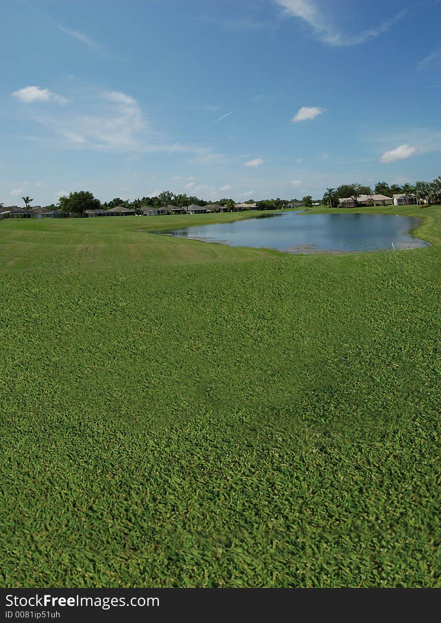 A lake view inside of a golfing community, with workers on the greens. A lake view inside of a golfing community, with workers on the greens.