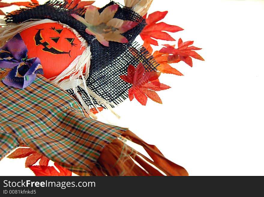 A scarecow and a scattered pile of colored fall leaves on a white background. A scarecow and a scattered pile of colored fall leaves on a white background