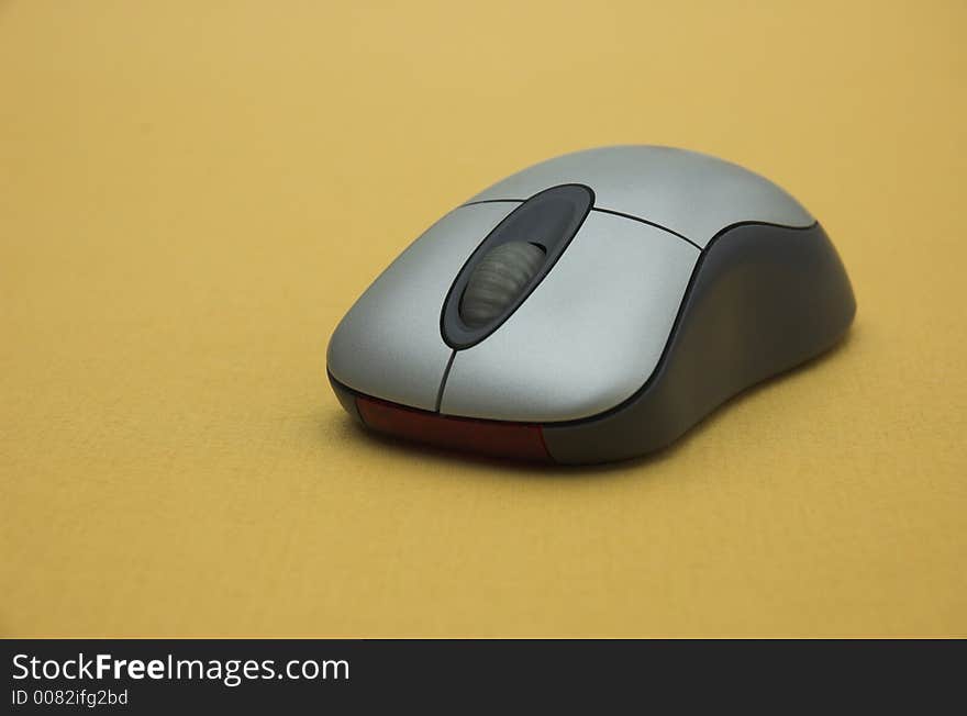 Wireless computer mouse on gold background.