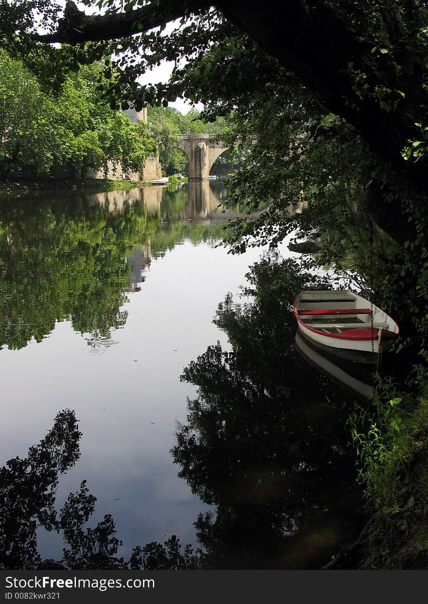 One small boat in a river, under a tree. One small boat in a river, under a tree