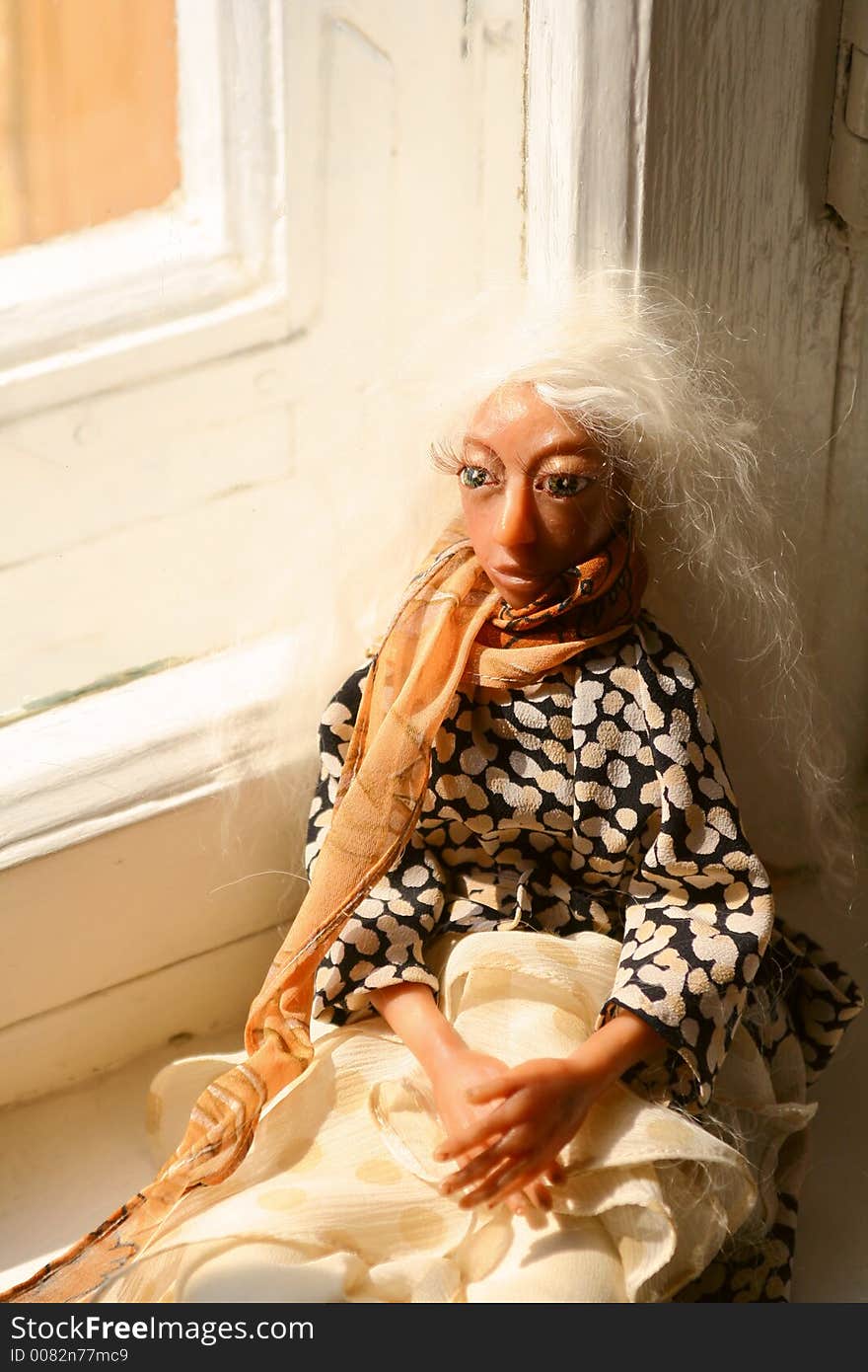 Old doll laying on a window sill. Old doll laying on a window sill