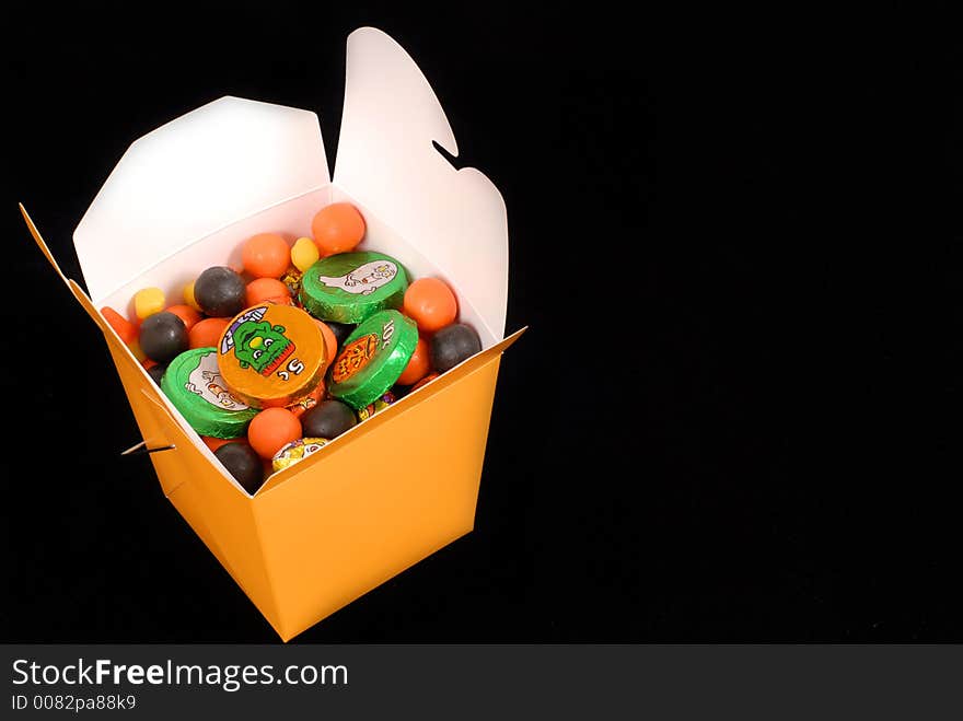 Halloween candy in an orange chinese food container isolated on black