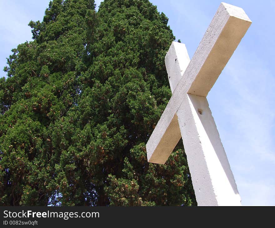 Stone cross and cypress with blue sky