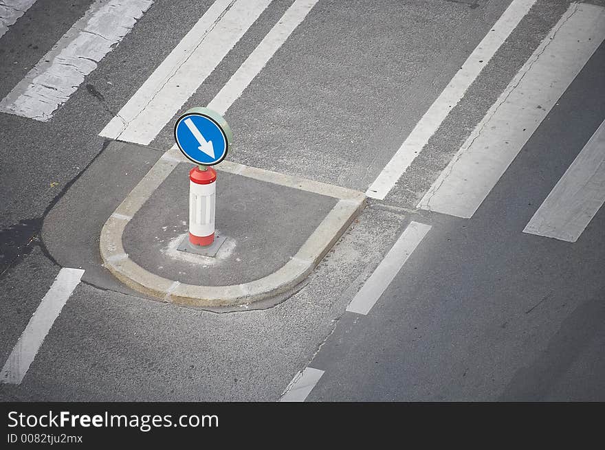 Two streets devided by a walkway with an direction sign on it. Two streets devided by a walkway with an direction sign on it