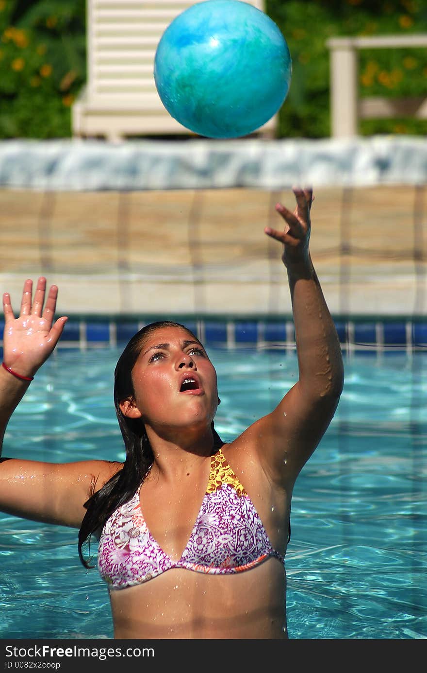 A girl is passing a ball in the pool. A girl is passing a ball in the pool