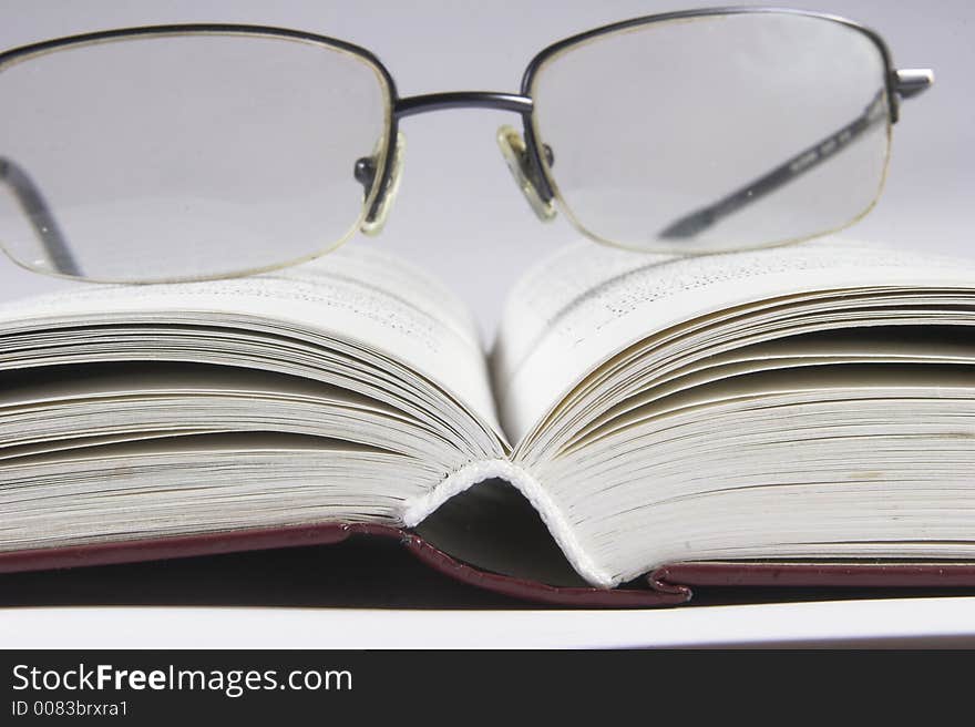 Eyeglass on book with white background