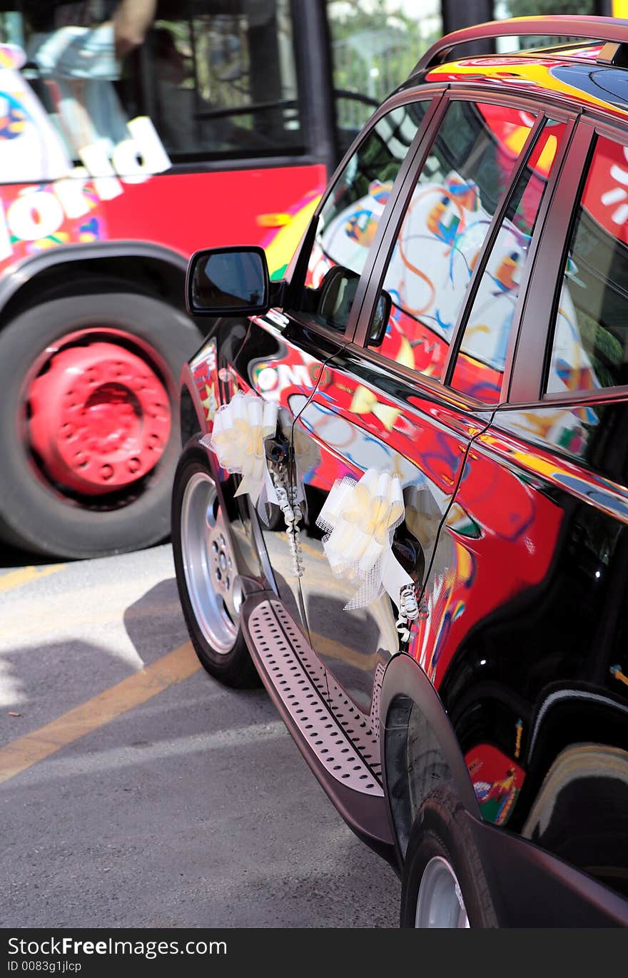 Colourful bus passing black wedding car