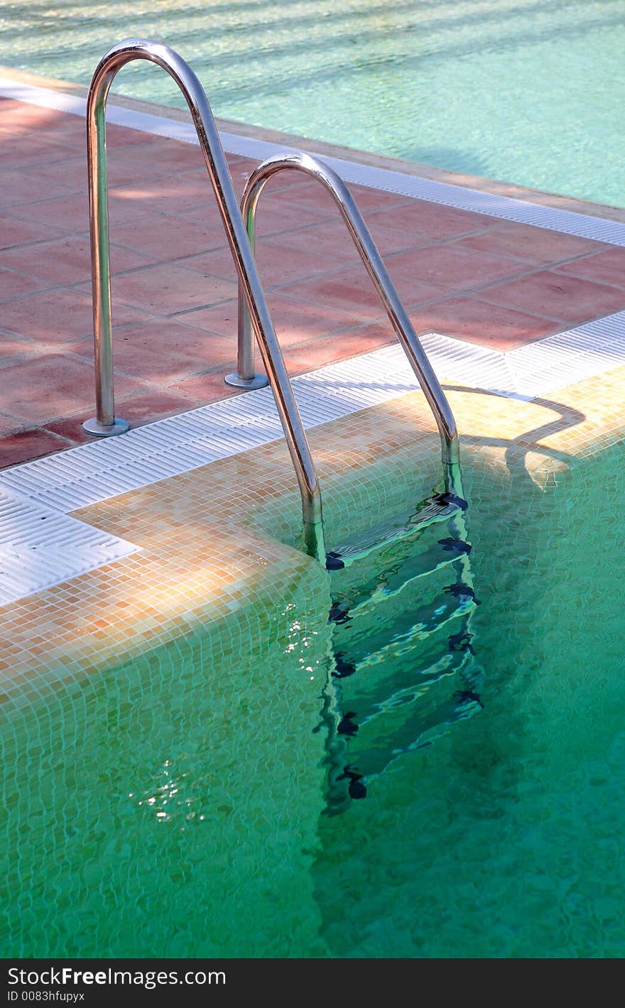 Steps leading out of clear green swimming pool