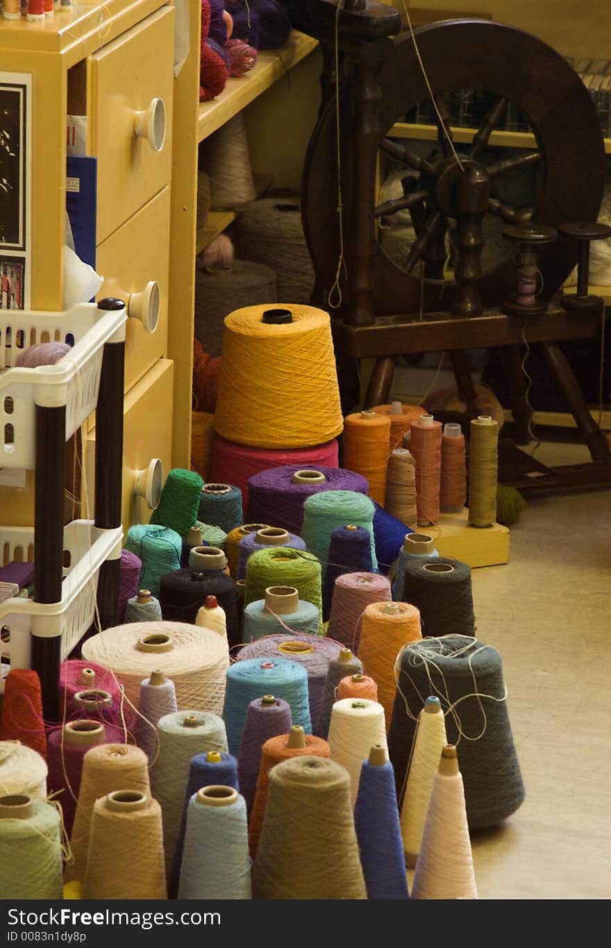 Spinning wheel and colorful yarns in a studio. Spinning wheel and colorful yarns in a studio