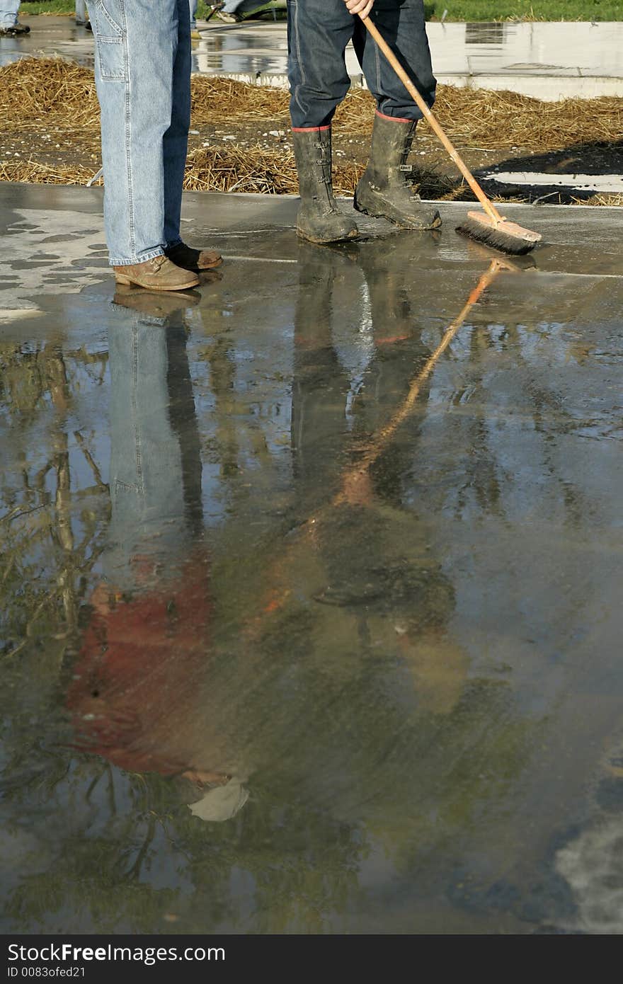 Two workers at a construction site reflected in wet concrete- room for text at bottom. Two workers at a construction site reflected in wet concrete- room for text at bottom