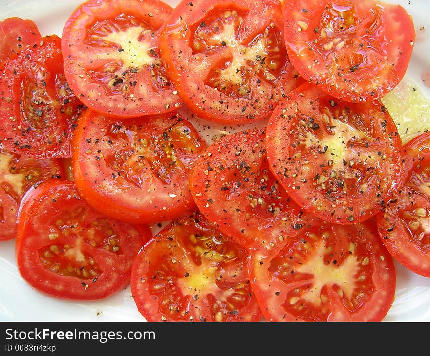 A plate of sliced tomatoes drizzled with olive oil and pepper. A plate of sliced tomatoes drizzled with olive oil and pepper