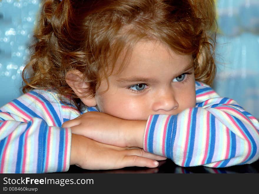 A young girl with big blue eyes and pigtails propping on her folded arms.