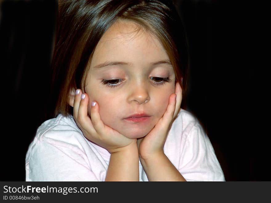 A beautiful young girl looking down with her hands on her face in deep thought. A beautiful young girl looking down with her hands on her face in deep thought.