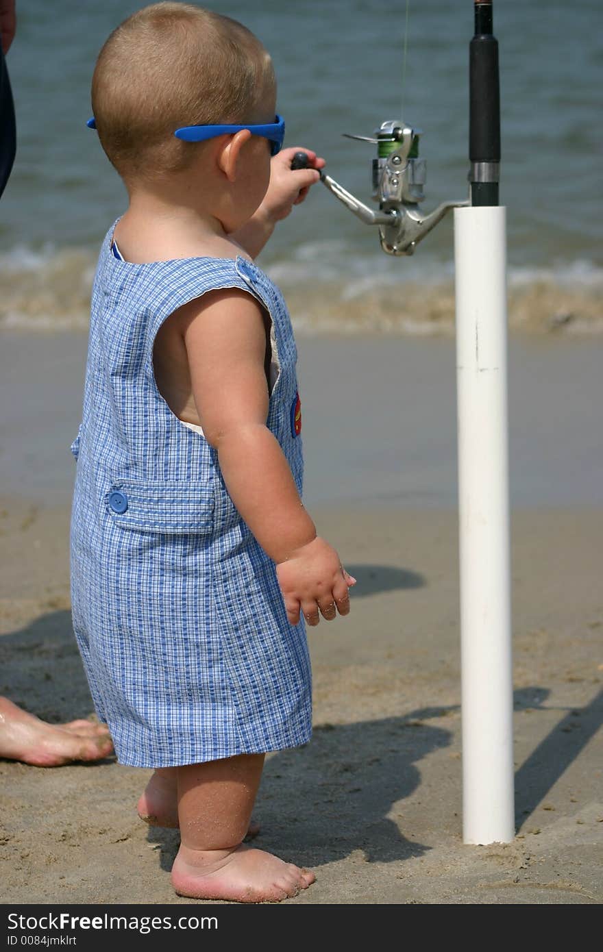 Young toddler baby with a fishing reel in his hand. Young toddler baby with a fishing reel in his hand