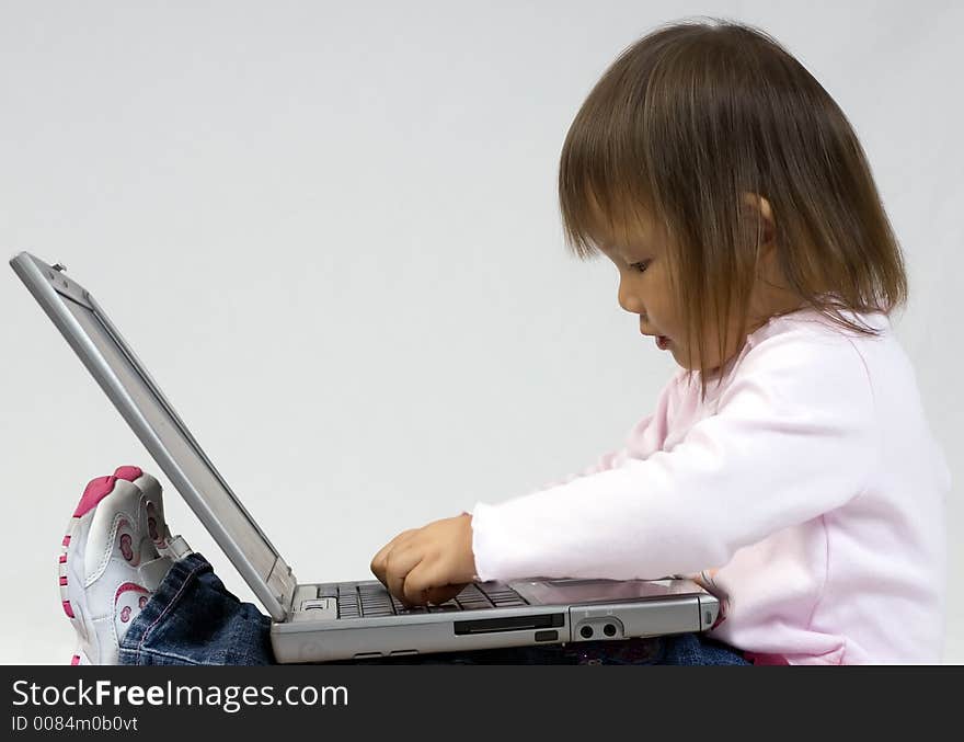 A young girl playing with a laptop computer. A young girl playing with a laptop computer