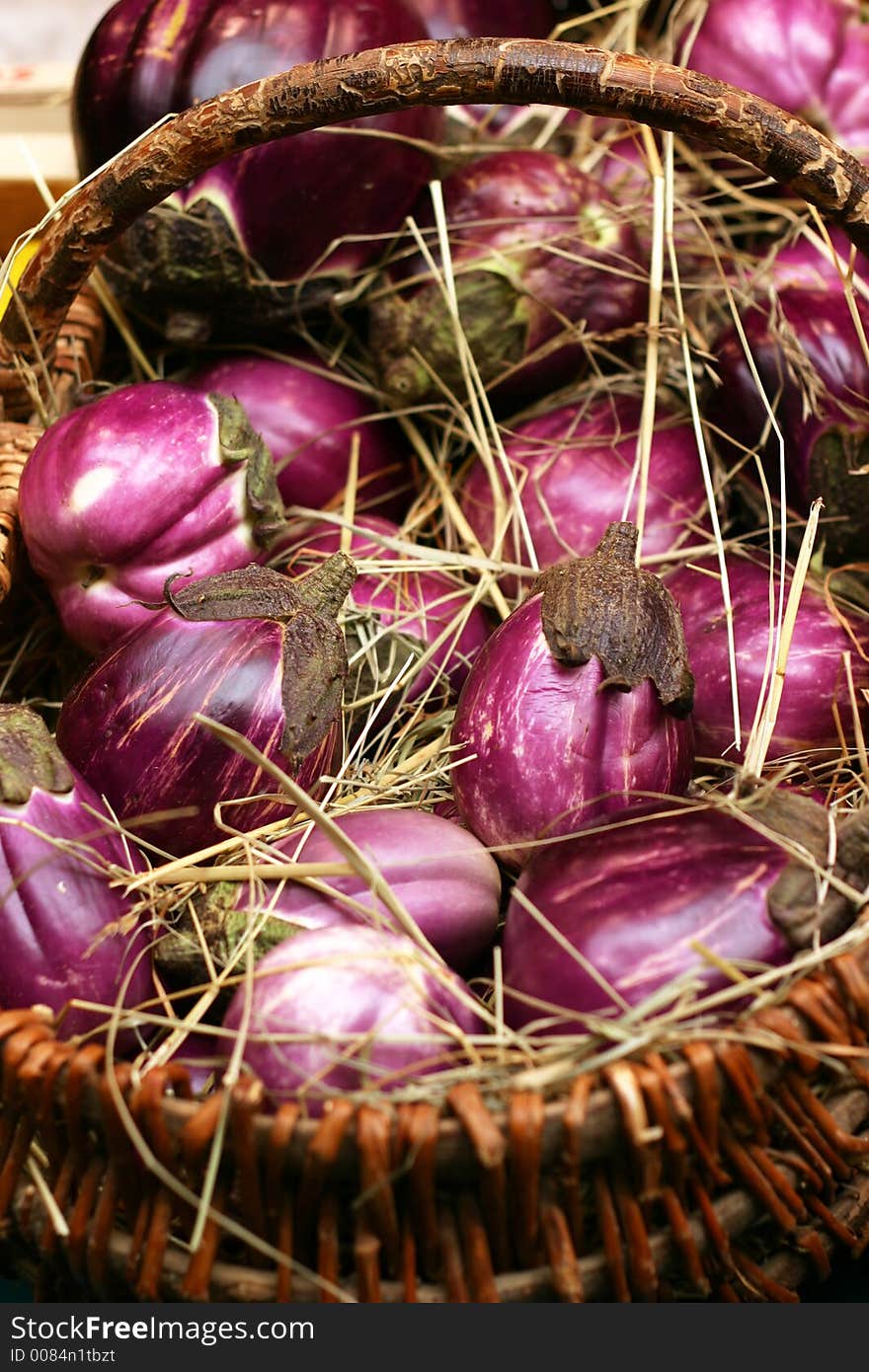 Colored eggplants in a basket with straw.