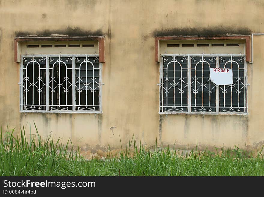 Ramshackle with signage on window, weeds growing high in garden. Ramshackle with signage on window, weeds growing high in garden.