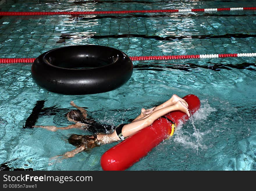 Indoor swimming pool fun, two girls playing with a big black buoy