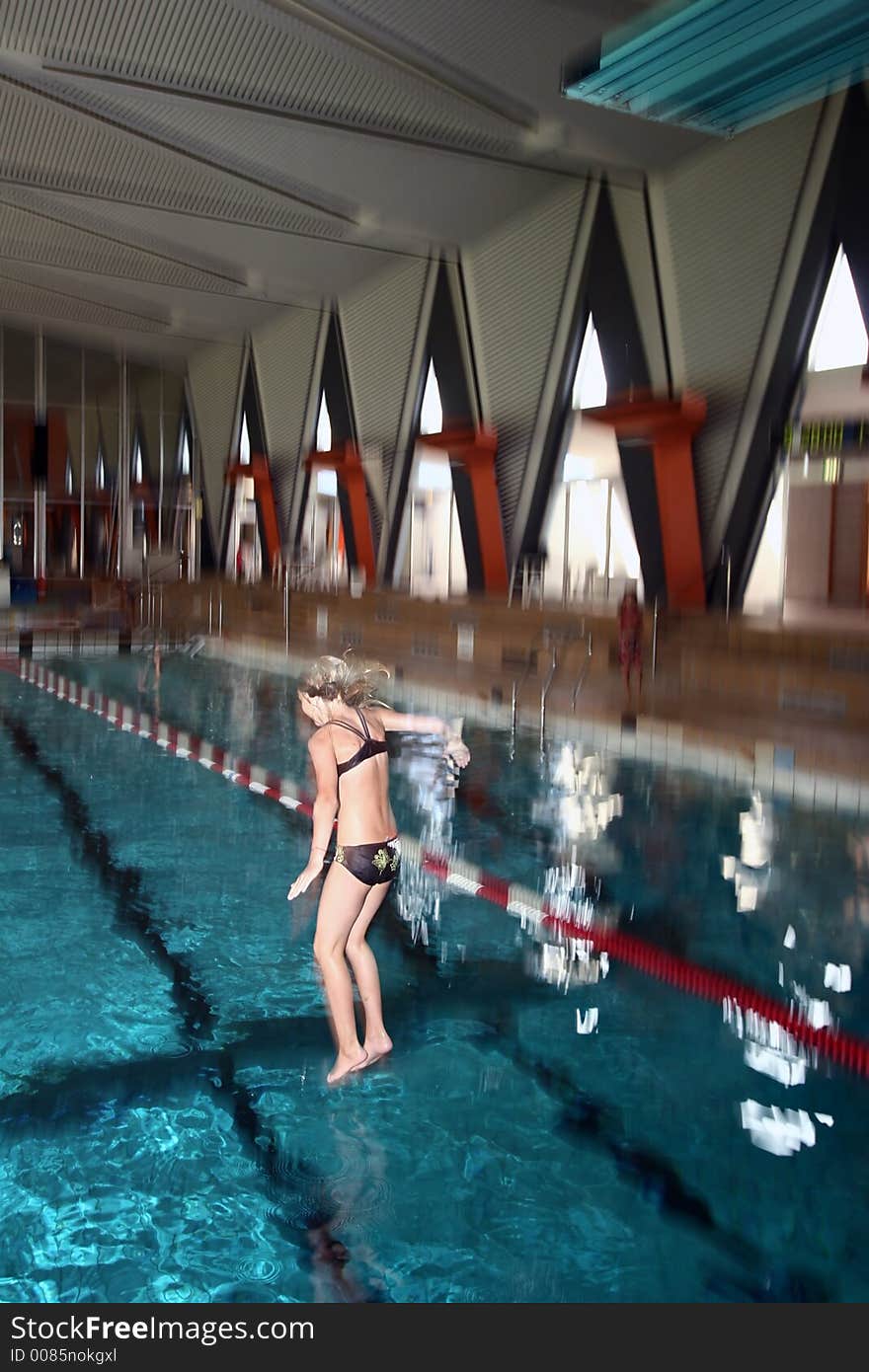 Indoor swimming pool fun, girl diving, motion blur