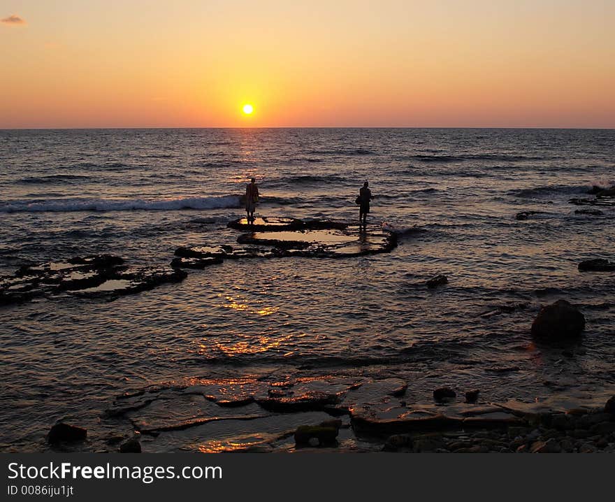 Fishers in a sunset sea