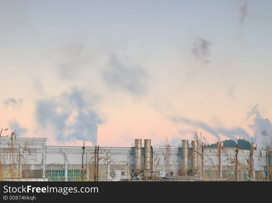 Factory belching out smog from its smokestacks lit by the evening light