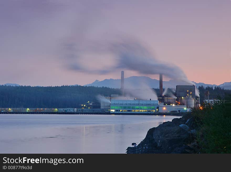 Factory belching out smog from its smokestacks lit by the evening light