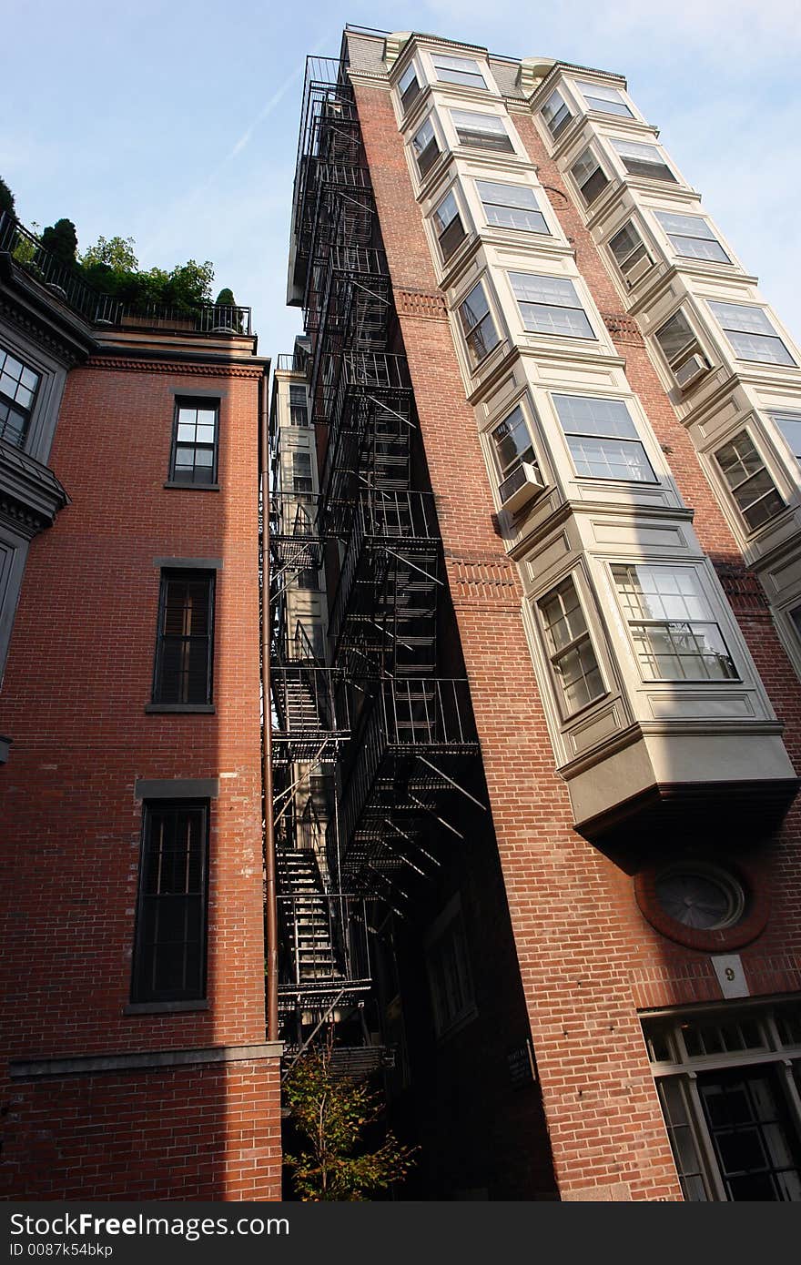 Image of an old tall apartment building in downtown boston showing two rows of bay windows and full fire escape. Image of an old tall apartment building in downtown boston showing two rows of bay windows and full fire escape