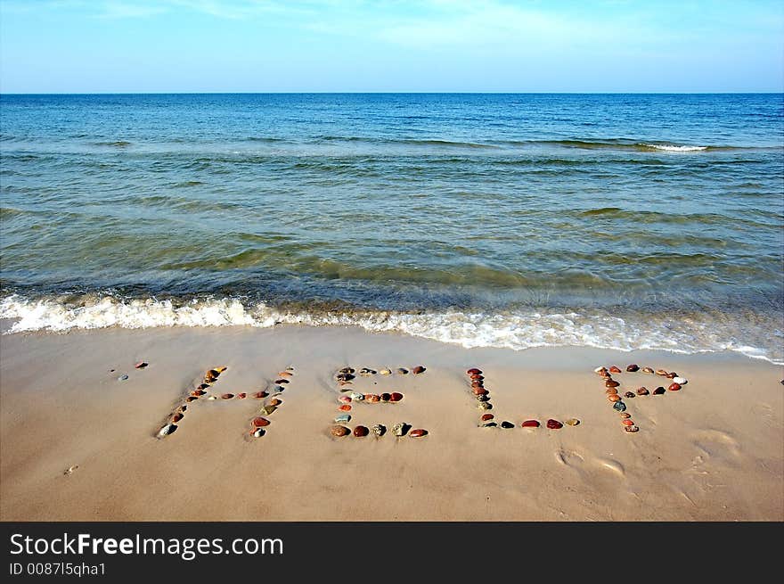 Word HELP on beach sand, made from rocks