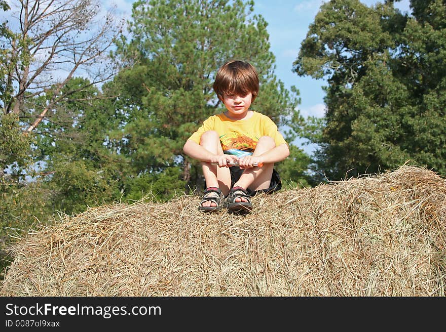 A young boy sitting ona  haybale. A young boy sitting ona  haybale