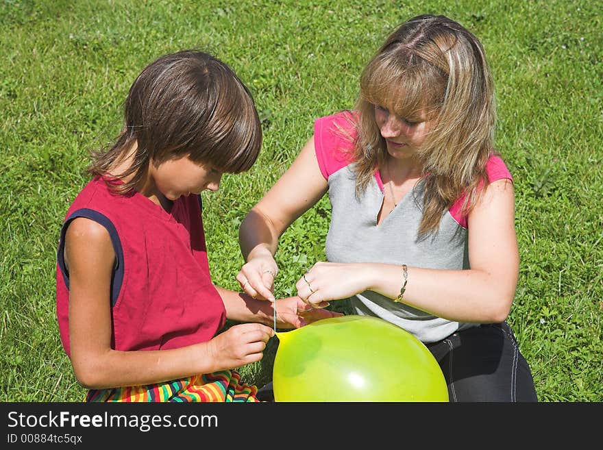 Boy and girl cheats varicolored air-ball in solar daytime