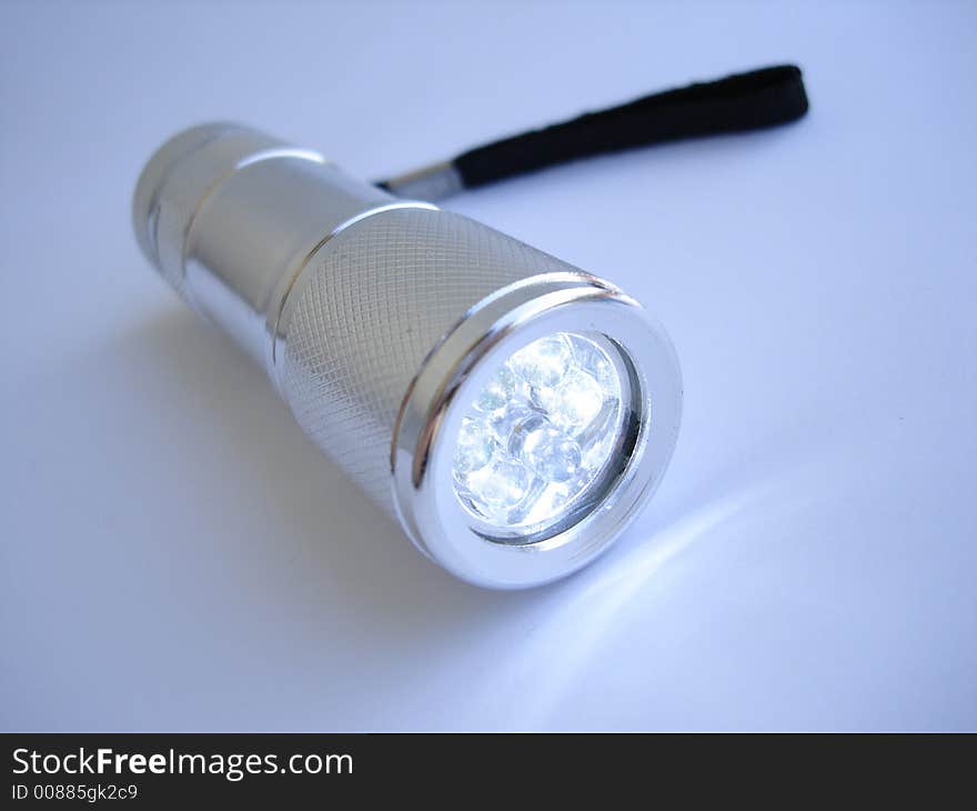 Silver metallic flashlight on blue background