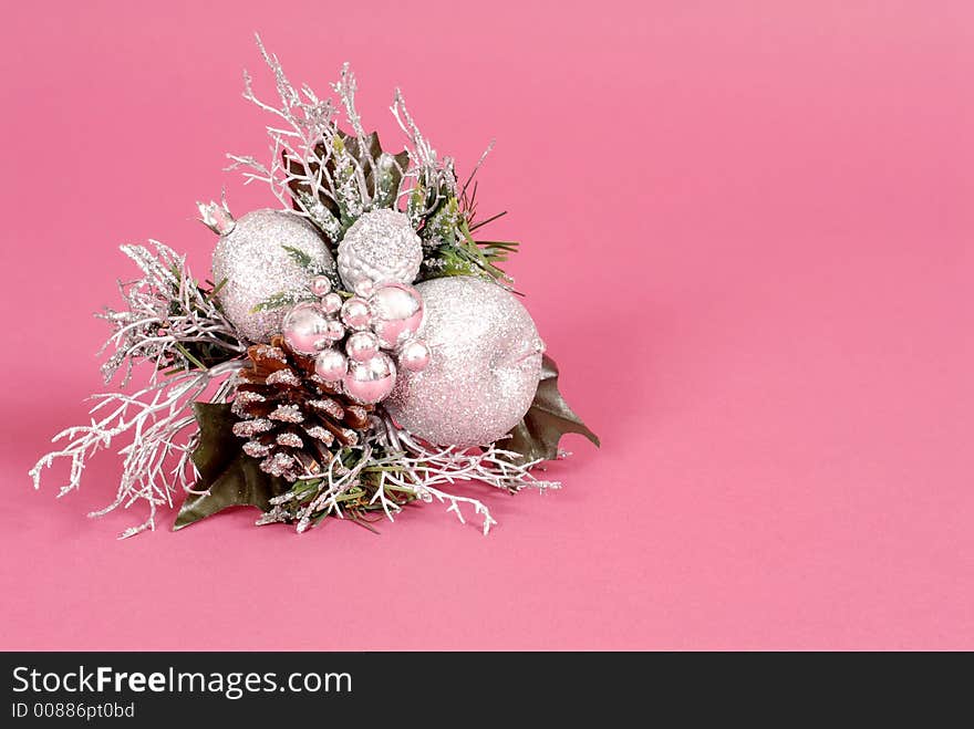 Silver Christmas ornament made of multiple balls, leaves, and pine cone on ruby background