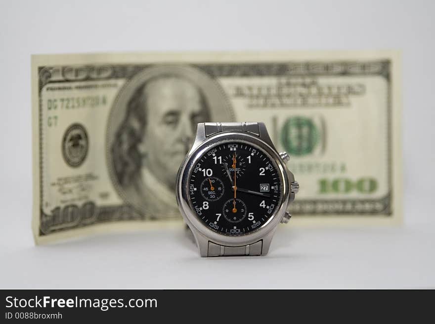 A wrist watch with the $100 bill in the background. Shallow depth of field, focus is on the watch. Time is money.