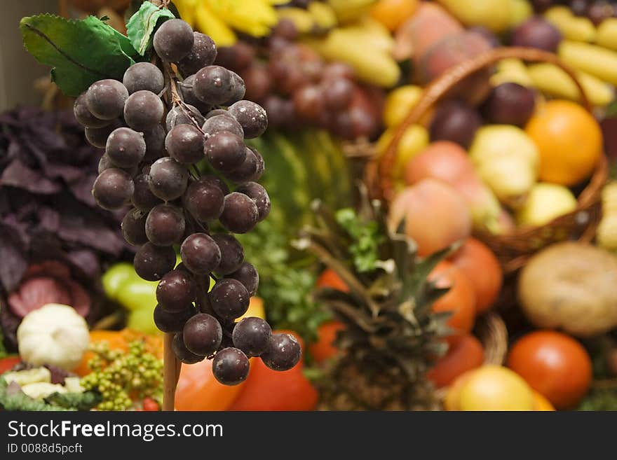 Grapes in front of a huge pile of other fruits and vegetables. Grapes in front of a huge pile of other fruits and vegetables