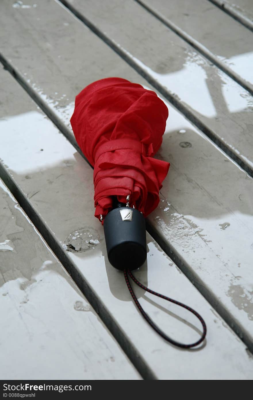 A picture of an unbrella left on a rain soaked porch. A picture of an unbrella left on a rain soaked porch.